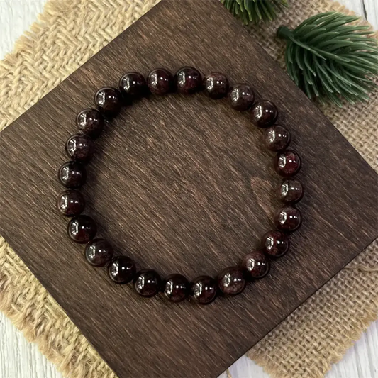 Dark red garnet beaded bracelet resting on a neutral surface for product display