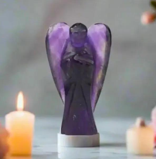 Carved amethyst angel figurine resting on a plain surface for spiritual altar decoration and meditation.