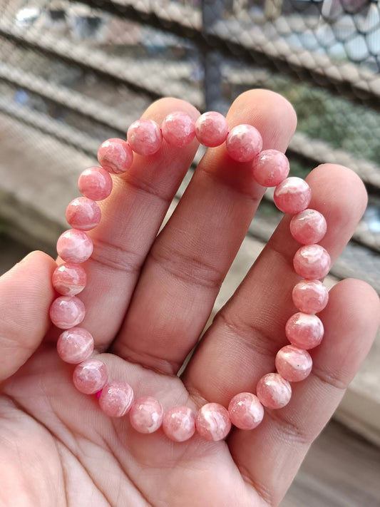 Natural rhodochrosite crystal with pink banding displayed for meditation and emotional healing practices