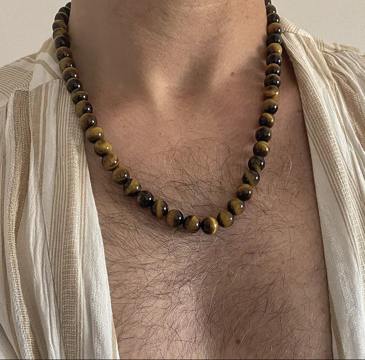 Healing crystal jewelry for men arranged on a dark textured surface
