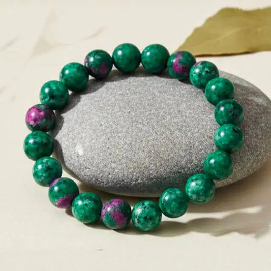 Ruby zoisite fertility bracelet with red and green crystal beads displayed on a neutral background.